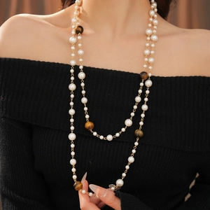 Detail of layered necklace with large tiger eye stone and white pearls on black fabric