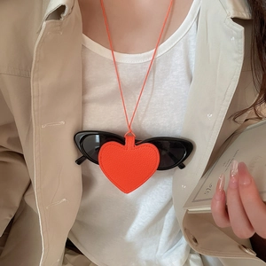 Close-up of heart-shaped red leather sunglasses holder necklace with lychee texture