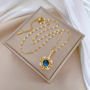 Detail of floral pendant with blue gemstone and diamonds on a gold flat chain link