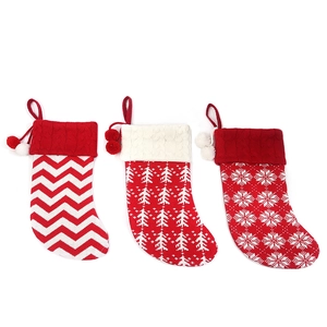 Three knitted Christmas stockings with red and white patterns and decorative pompoms