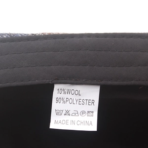 Close-up of washing label showing 10% wool and 90% polyester blend on newsboy hat