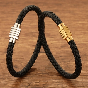 Detail of black braided leather bracelets with silver and gold magnetic metal clasps