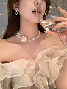 Detailed view of elegant triple-layer resin pearl necklace with side camellia flower design