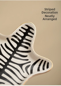 Detail of star-shaped ceramic jewelry tray with zebra stripes and elegant gold-plated edges