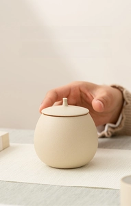 Detail of matte beige ceramic tea canister with transparent inner glaze for freshness