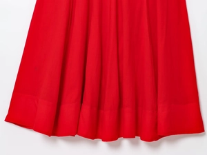 Detailed close-up of the wide stitched hem on a red cotton midi dress with clean texture