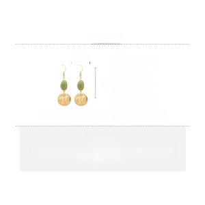 Détail de boucles d'oreilles en résine avec sphères dorées et perles vert olive
