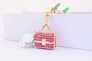 Detail of golden bag keychain with pink rhinestones, resin rose, and pearl charms