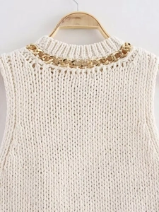 Detail of white knit sleeveless top featuring chunky gold metal chain on the neckline
