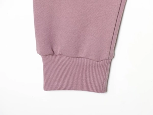 Gros plan sur maille de coton mauve avec poignets côtelés élastiques et coutures fines
