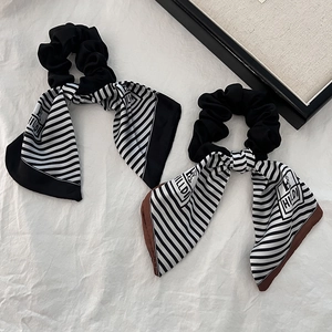 Close-up of black scrunchies with elegant black and white striped silk scarves and logo detail