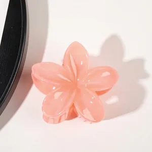 Detail of a glossy pink flower hair claw clip with gradient petals and gold metal spring