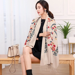 Close-up of beige pashmina with colorful floral embroidery and soft tassel details