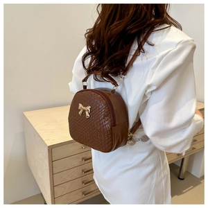 Dettaglio dello zaino mini in pelle intrecciata marrone con fibbia a farfalla dorata