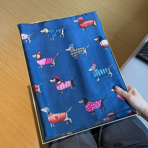 Close-up of a navy cotton linen scarf with cartoon dachshund patterns in a gift box