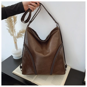 Close-up of deep brown PU leather shoulder bag with diagonal zipper details and strap