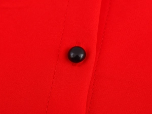 Close-up of black button and collar detail on a red sleeveless mini dress fabric