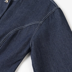 Gros plan sur le denim bleu foncé avec coutures blanches contrastées et bouton doré