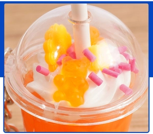 Macro shot of faux orange tea keychain with resin bear, cream topping, and star fruit