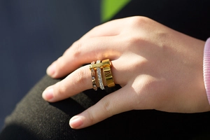 Detail of stacked Roman numeral rings in gold and rose gold finish with zircon inlay