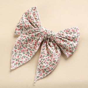 Detail of fabric bow hair clip featuring a delicate pink floral print on beige cotton