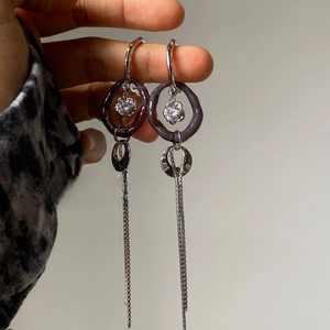 Detail view of long tassel earrings with purple rings and sparkling zircon crystal charms