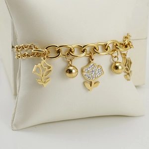 Gold stainless steel rose flower bracelet with sparkling crystals on jewelry pillow