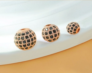 Macro shot of three rose gold copper beads with black zircon pavé grid for DIY bracelets