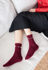 Detail of burgundy ruffled ankle socks with elegant pearl embellishments on the trim
