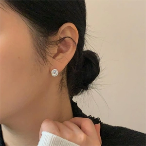 Close-up of minimalist silver irregular textured earrings on model's ear