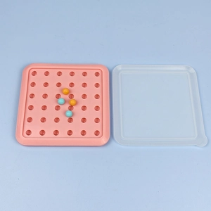 Pink silicone round mold tray with clear lid and colored spheres on a blue background