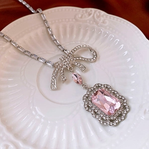 Close-up of silver necklace with pink crystal square pendant and diamond bow design