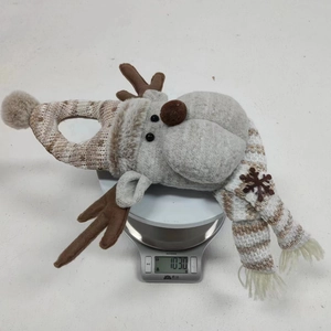 Detail shot of a plush reindeer holiday decoration weighing 103g on a digital scale