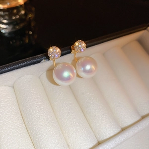 Detailed macro view of gold-plated geometric earrings with zircon and large white pearls
