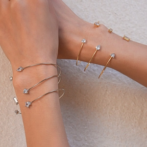 Détail de bracelets joncs dorés et argentés avec des zircons en forme d'étoile et poire