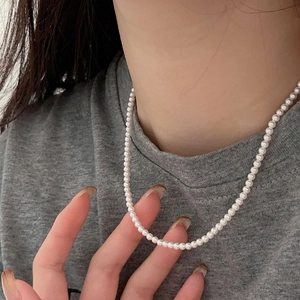 Minimalist 925 sterling silver necklace with white pearls on a grey fabric background