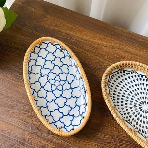 Macro view of blue floral ceramic oval plate with handcrafted rattan woven border