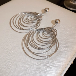 Detailed view of silver multi-layered concentric metal hoop earrings on white texture