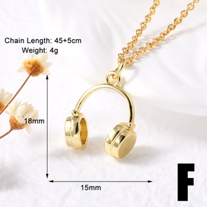 Macro shot of gold-plated headphone pendant necklace with size measurements on white surface
