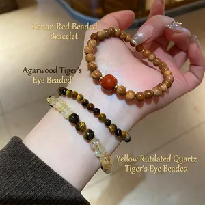 Hand wearing yellow rutilated quartz and tiger eye beaded bracelets in warm lighting