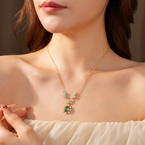 Détail d'un collier vintage doré avec zircon ovale vert et perles bleu clair