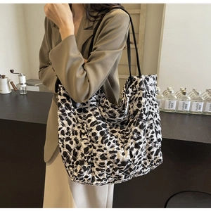 Detail of leopard print quilted tote bag worn by a model in a cozy cafe setting
