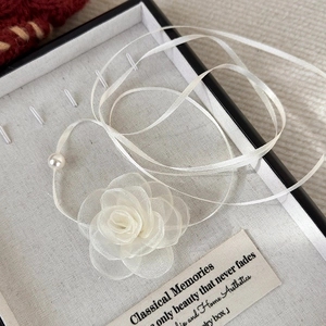 Macro shot of white fabric rose choker with pearl charm in a luxury jewelry gift box