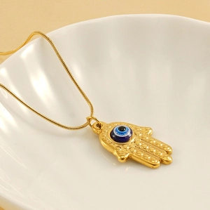 Detail of golden Hamsa Hand pendant with blue Evil Eye on a sleek snake chain