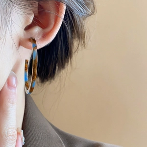 Close-up of vintage resin C-shape hoop earrings with brown and blue marble pattern