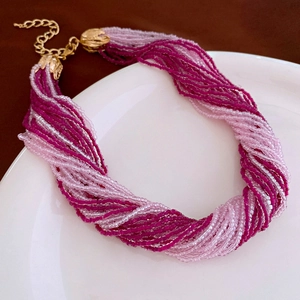 Macro shot of multi-layer pink seed bead twisted necklace with golden lobster clasp