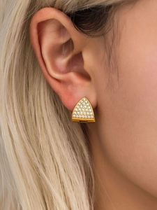 Macro shot of gold triangular earrings with white zircon crystals on a female model