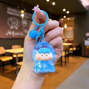 Détail d'un porte-clés dessin animé bleu avec boule acrylique et paillettes brillantes