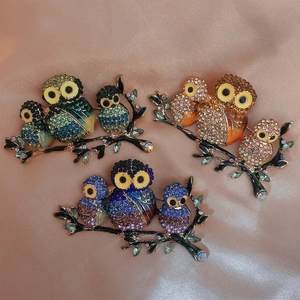 Macro detail of three crystal owl brooches on silk, showing intricate rhinestone settings