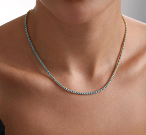 Close-up of elegant gold tennis necklace with square blue cubic zirconia stones on neck